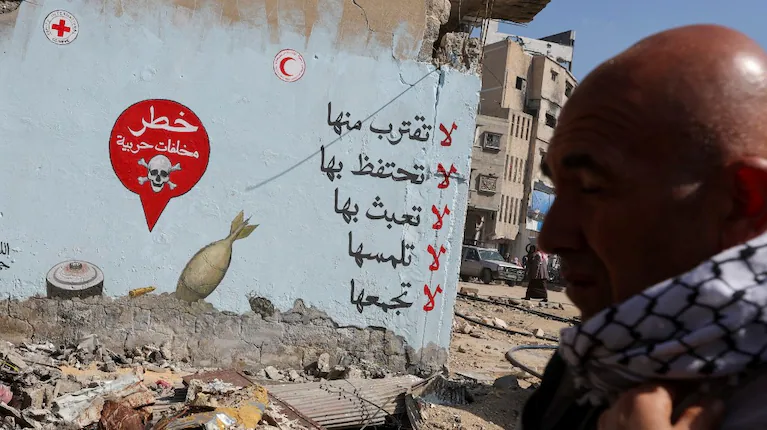un-hombre-pasa-junto-a-un-mural-de-la-cruz-roja-que-advierte-a-la-gente-sobre-la-proximidad-de-artefactos-explosivos-en-khan-younis-en-el-sur-de-la-franja-de-gaza-reutersramadan-abed-NUWGRRN57BERZENSKJJOUCINWM